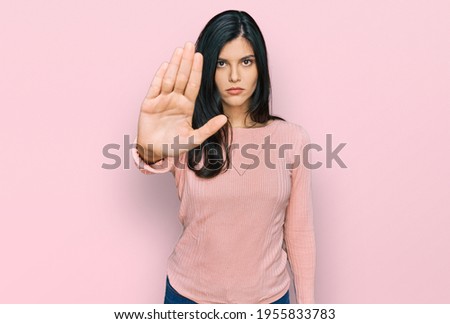 Young hispanic woman wearing casual clothes doing stop sing with palm of the hand. warning expression with negative and serious gesture on the face. 