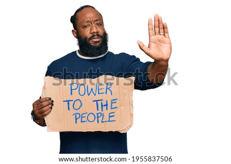 Young african american man holding power to the people banner with open hand doing stop sign with serious and confident expression, defense gesture 