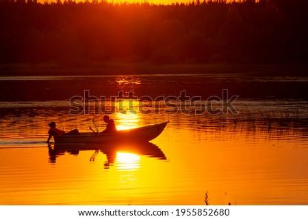 Silhouettes of people in a boat at sunset.