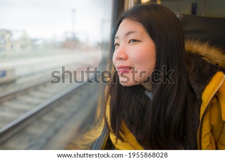young beautiful and happy Asian Japanese woman sitting on train looking out to window enjoying holidays travel in Europe smiling thoughtful and sweet