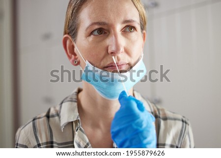 Doctor Carrying Out Rapid Lateral Flow Test For Covid-19 On Mature Woman In Surgery Wearing Mask Royalty-Free Stock Photo #1955879626
