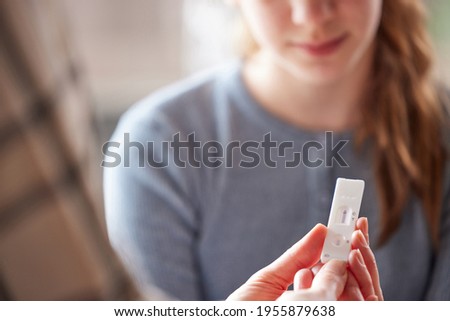 Mother And Daughter Looking At Negative Rapid Lateral Flow Test For Covid-19 On Daughter At Home Royalty-Free Stock Photo #1955879638
