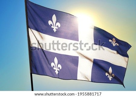 Quebec province of Canada flag waving on the wind in front of sun
