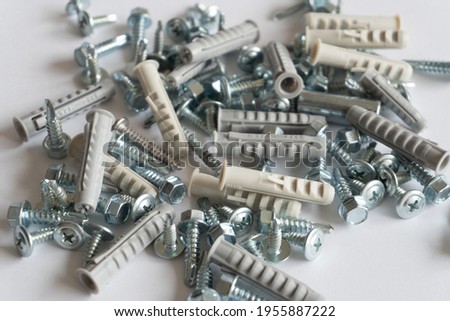 Screws and wall plugs piled up on a white background. Work concept