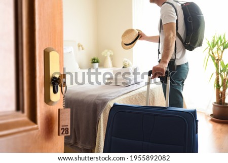 Man on vacation entering a bright hotel room with open door and key set Royalty-Free Stock Photo #1955892082