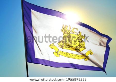 Newark of New Jersey of United States flag waving on the wind in front of sun