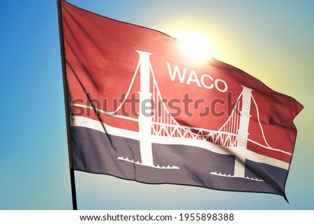 Waco of Texas of United States flag waving on the wind in front of sun