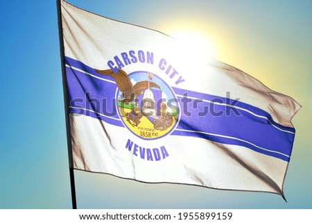 Carson of Nevada of United States flag waving on the wind in front of sun