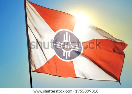 Wichita of Kansas of United States flag waving on the wind in front of sun