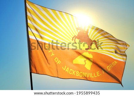 Jacksonville of Florida of United States flag waving on the wind in front of sun