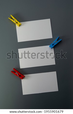 three blank business cards and clothespins lie on a gray background. Cover.
 Business concept.