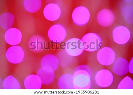 Blurred view of violet lights on red background. Bokeh effect