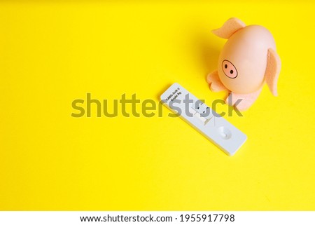 Cheerful pig egg with negative covid test on yellow background. Easter concept. Lots of free space. Easter quarantine. Stay at home