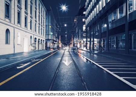Streets of Geneva downtown by rainy night : Tram track and leading lines at night from the middle of the road.