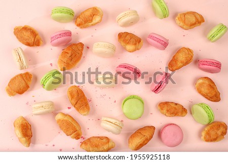 Fresh ruddy and colorful macaroons croissants on a light table with crumbs, Top view, place for text. Modern bakery concept, business card for advertising or invitation. Delicious traditional breakfas