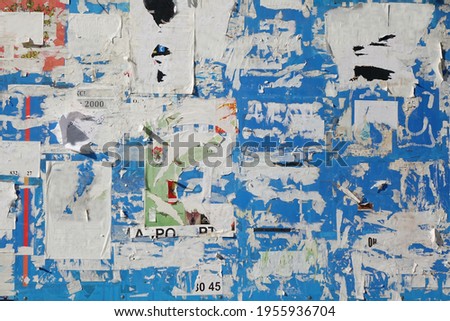 Old Billboard with Torn Posters. Dirty Street Wall with Crumpled, Wrinkled, Creased, Worn and Torn Posters. Abstract Vintage Background and Texture.
