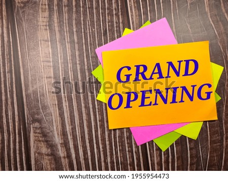 Grand opening, the phrase is written on multi-colored stickers, on a brown wooden background. Business concept, strategy, plan, planning.