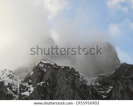 Misty mountains. Snowed rock mountains with fog and blue sky. 