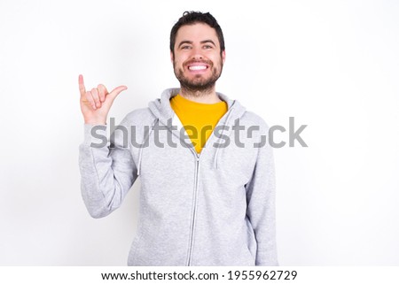 Young caucasian man wearing tracksuit over white background showing up number six Liu with fingers gesture in sign Chinese language