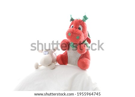 Soft cuddly toys red Welsh dragon with green ears and white stuffed sheep with high key white background.