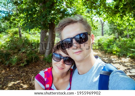Romantic couple in sunglasses making selfie while walking in the summer forest. Local Traveling and relax in nature. Digital detox. Offline life. Capture the moment. Enjoy life. Copy space.