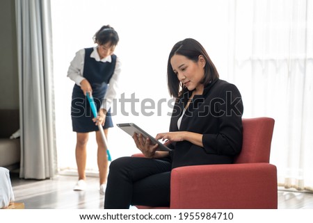Housekeeping manager with tablet checking maid work in hotel room,Hotel manager controlling how maid working. Royalty-Free Stock Photo #1955984710