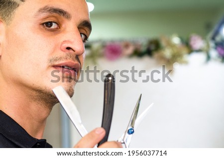 Barber Shop. Barber holds a razor to shave his beard. Boy with vintage razor.