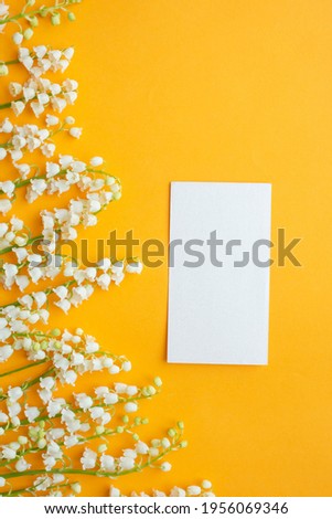 greeting card on background with lily of the valley on yellow table