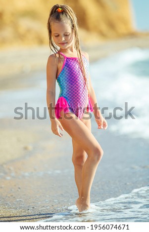 Child at sea. Children's fashion. Child in a swimsuit on the beach. High quality photo.
