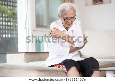 Itchy senior woman scratching arms with her hands,rash on body,pruritus,severe itching of the skin from food allergies,symptoms of hives,urticaria disease,patient allergic reaction,atopic dermatitis Royalty-Free Stock Photo #1956114376