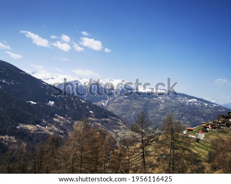Scenic panorama of Herens Valley in Spring in Swiss Alps - Snow is melting in woods and remaining above the trees