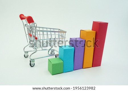 Five colored squares in a row shaped like a diagram and a miniature shopping trolley isolated on a white background