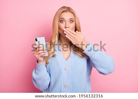 Photo portrait of woman wavy hair staring shut mouth with hand keeping secret isolated on pastel pink color background