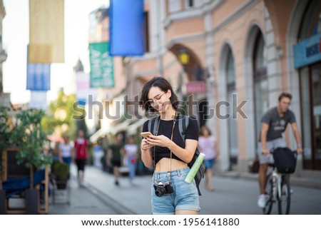 Tourist woman in the city.  Young woman on street typing on smart phone. 