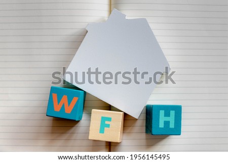 Work from home concept, Selective focus of colourful wooden blocks alphabet with abbreviations word WFH, Multicolour wood cube on house top of opened notebook, Free copyscape for your text.