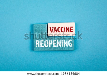 Reopening and Vaccine. Health and business concept. Wooden cubes with text on a blue background.