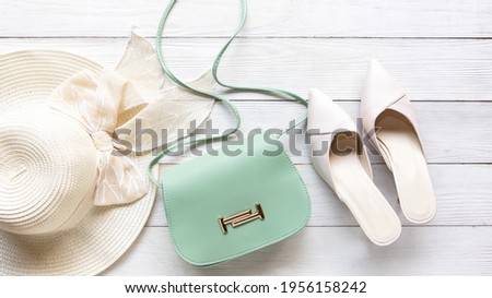 Fashion blue bag woman accessories set. Trendy green and white fashion with big hat on wood white background. Fashion Concept.