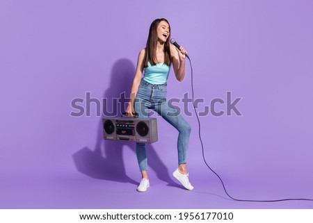 Full size photo of happy nice young woman sing song microphone hold cassette player isolated on violet color background