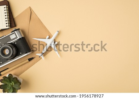 Top view photo of flowerpot pen notebooks camera and plane model on craft paper envelope on isolated beige background with copyspace