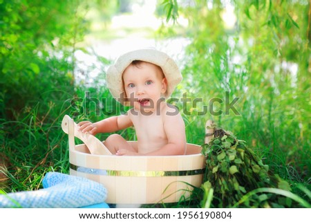 beautiful child boy in a hat bathes in a wooden basin in warm weather blows bubbles. happy summer. Holidays in the countryside outdoors
