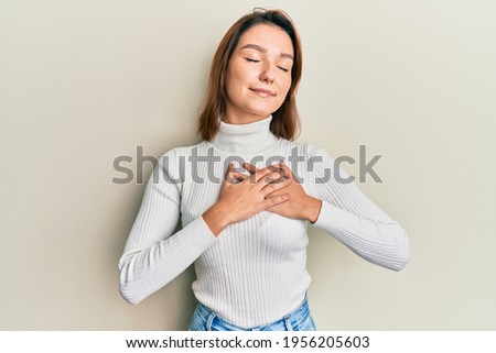 Young caucasian woman wearing casual clothes smiling with hands on chest, eyes closed with grateful gesture on face. health concept. 
