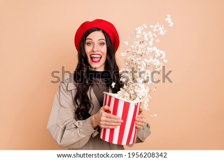 Photo portrait of excited girl throwing popcorn from big bag isolated on pastel beige colored background