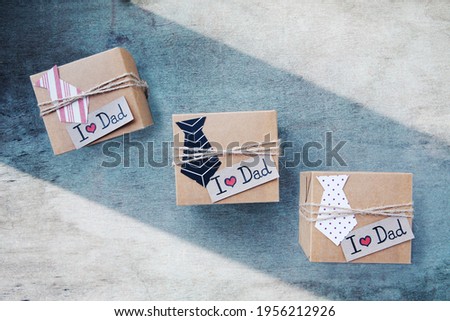 Handmade craft gift boxes with different paper tie, text I love dad on blue wooden background. Concept International Father's day, birthday. Minimalism. Top view, copy space, vertical image