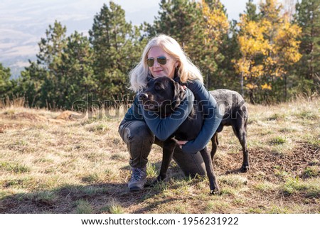 Blond woman and black dog in a mountain landscape on a sunny day