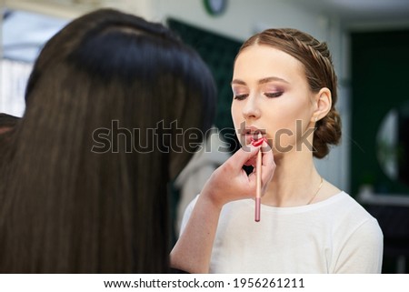 Getting ready for party. Professional make-up artist painting female clients' lips in pale pink color. Work process in beauty studio. Love yourself retreat Close-up picture on make-up model.