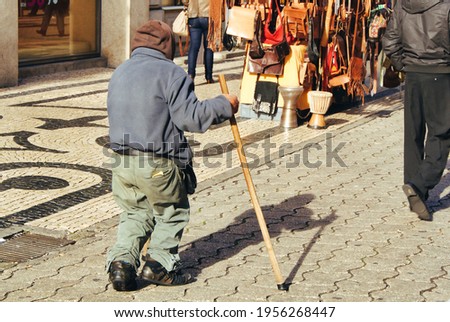 Old lame tramp walks holding a stick.
Back view of a poor man trudging on a shopping street. Royalty-Free Stock Photo #1956268447