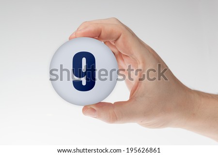 Man's hand holding white styrofoam ball with number 9  against the white background.