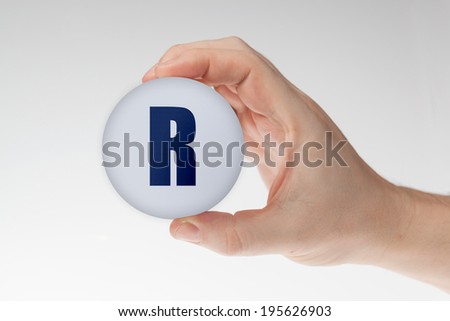 Man's hand holding white styrofoam ball with letter R against the white background.