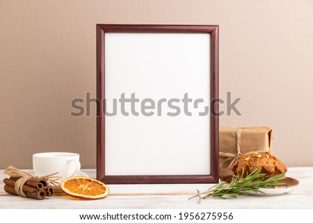 Brown wooden frame mockup with cup of coffee and cake on brown background. Blank, side view, still life.