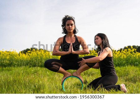 yoga teacher helps student perform yoga exercise in nature with the help of a yoga element
